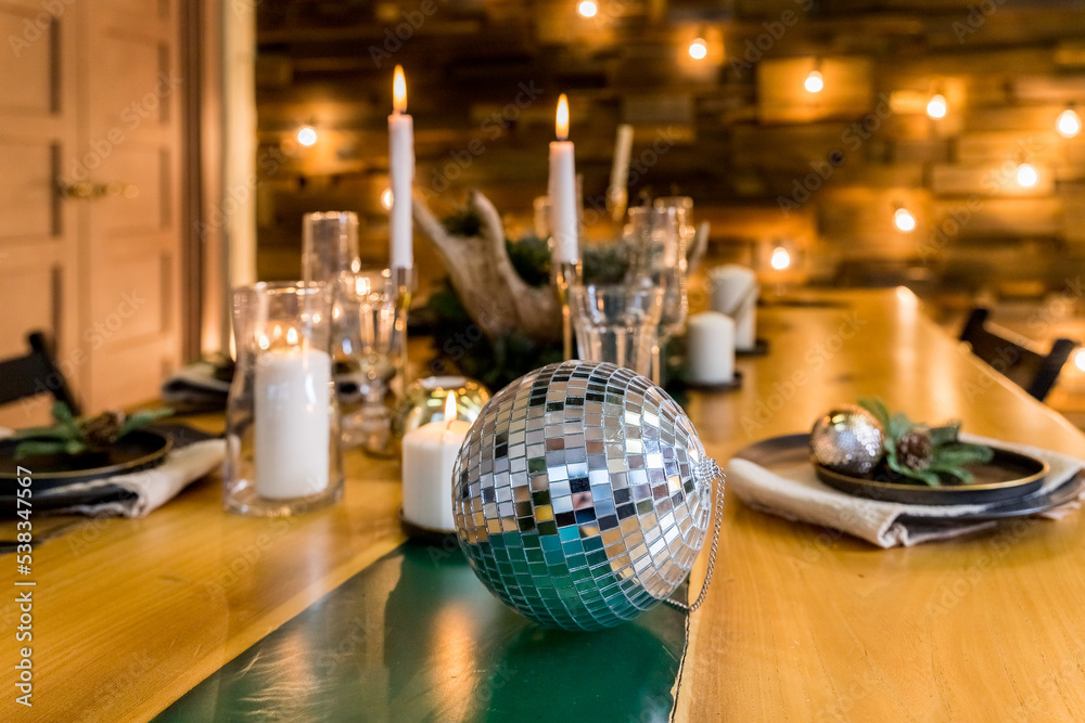 mirror ball, white candles and Christmas decor on wooden table.kitchen is decorated in a Christmas style with white accents. Cozy atmosphere of winter holidays.New Year holiday concept.
