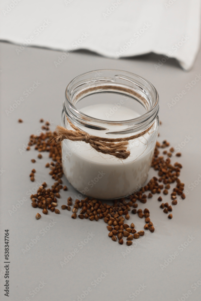 Jar with vegan milk and buckwheat. Eco and animal friendly eating concept. Healthy food, diet. Lactose free. Soft focus. Vertical