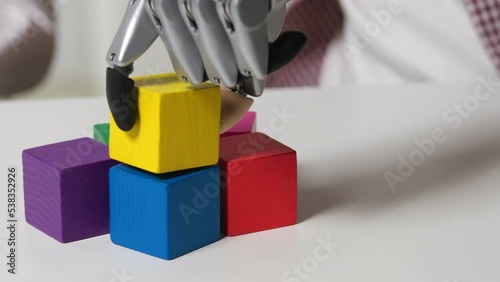 Man with bionic hand prosthesis build tower with colored wooden blocks at rehabilitation session photo