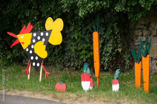 décoration extérieures dans un petit village avec une poule, des légumes, radis, carottes, découpés dans des planches en bois et peints avec des couleurs vives photo