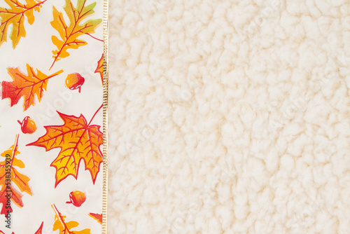 Red and orange fall leaves border autumn background on beige sherpa material