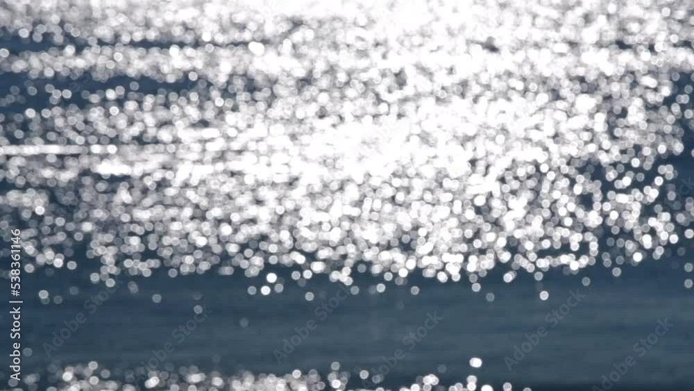 Abstract blurred background.Spots of white reflections of shining sun on blue surface of sea waves.Sea on sunny day.Natural blurry bokeh texture backdrop.Seamless looping.Beautiful natural background Abstract blurred background.Spots of white reflections of shining sun on blue surface of sea waves.Sea on sunny day.Natural blurry bokeh texture backdrop.Seamless looping.Beautiful natural background