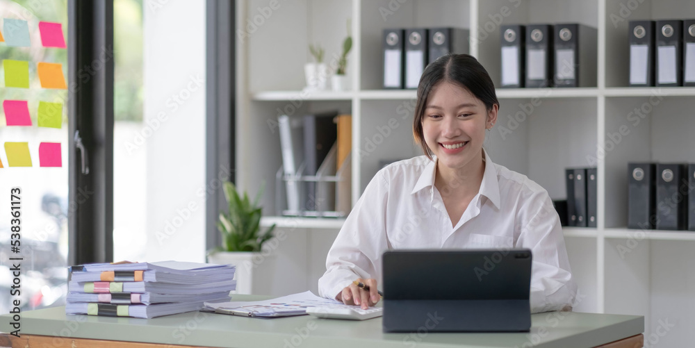 Asian Businesswoman Using laptop computer and working at office with calculator document on desk, doing planning analyzing the financial report, business plan investment, finance analysis concept.
