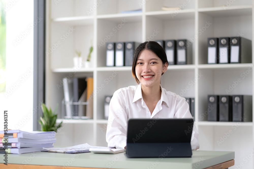 Charming Asian woman working at the office using a laptop Looking at the camera. Charming Asian woman working at the office using a laptop Looking at the camera.