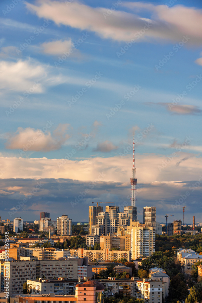 City landscape in the rays of the setting sun. The TV tower rests against the cloudy sky.