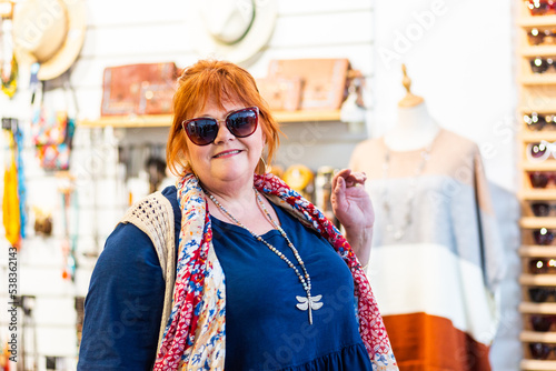 Happy middle age woman in store trying on sun glasses photo
