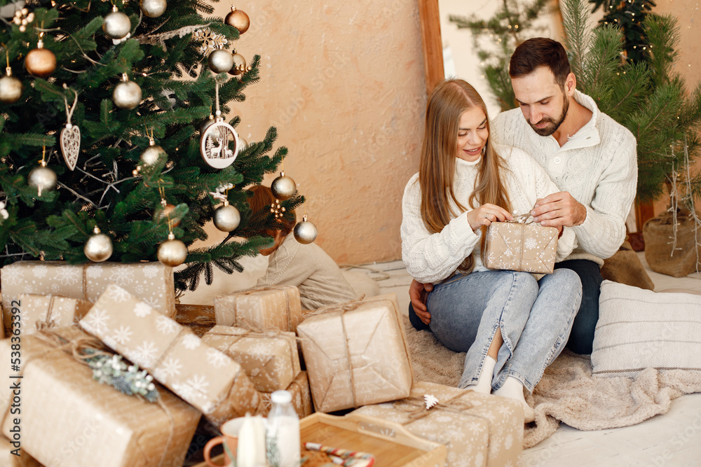 Romantic couple sitting on a floor near Christmas tree at home Romantic couple sitting on a floor near Christmas tree at home