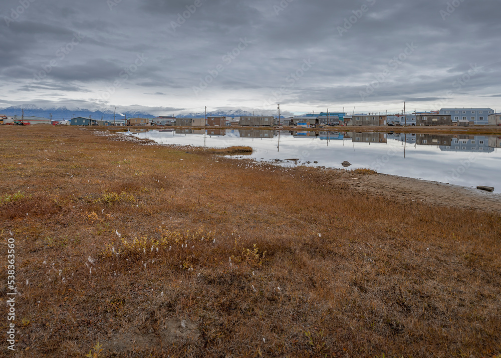 Pond Inlet houses reflected in a tundra pond with the Byam Martin Mountains in the background