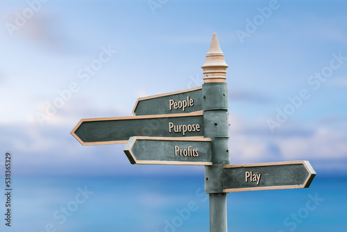 people purpose profits play four word quote written on fancy steel signpost outdoors by the sea. Soft Blue ocean bokeh background.