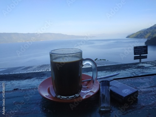 a cup of coffee and a cigarette in the morning with a cool and peaceful atmosphere on lake toba photo