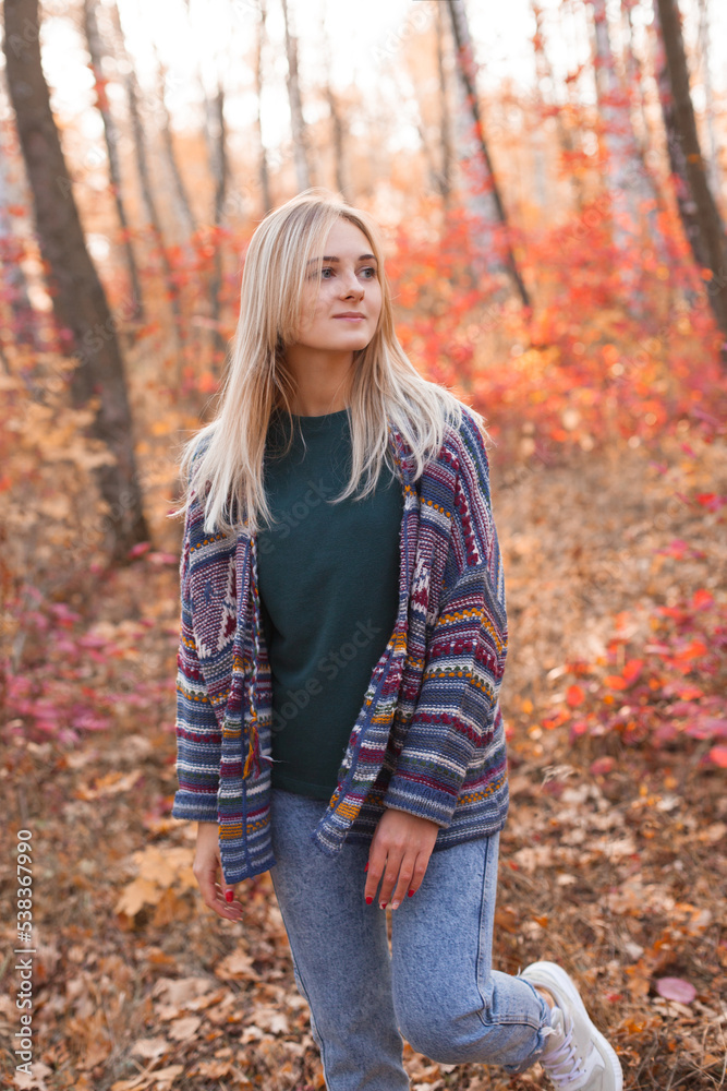 Young beautiful woman in knitted cardigan walking in the autumn forest. Young beautiful woman in knitted cardigan walking in the autumn forest.