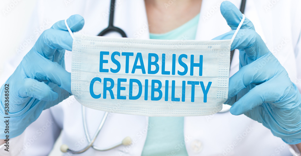 ESTABLISH CREDIBILITY text on a protective mask in the hands of a doctor, medical concept ESTABLISH CREDIBILITY text on a protective mask in the hands of a doctor, medical concept