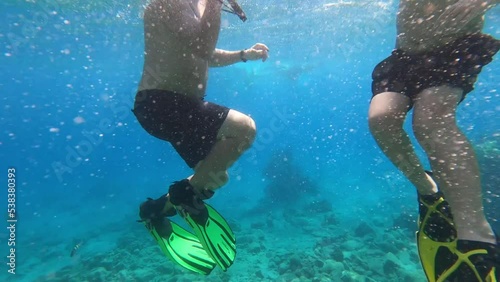 Close-up of unique, amazing, underwater world of sea with beautiful corals and colorful fish. Men swims underwater and waving. Diving, active tourism and rest. Blue, clear water. 