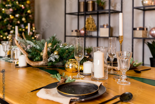 A large wooden table served for Christmas dinner in country house. new year with friends and family.festive dinner. Table setting and decoration with candles, spruce branches and christmas ornaments.