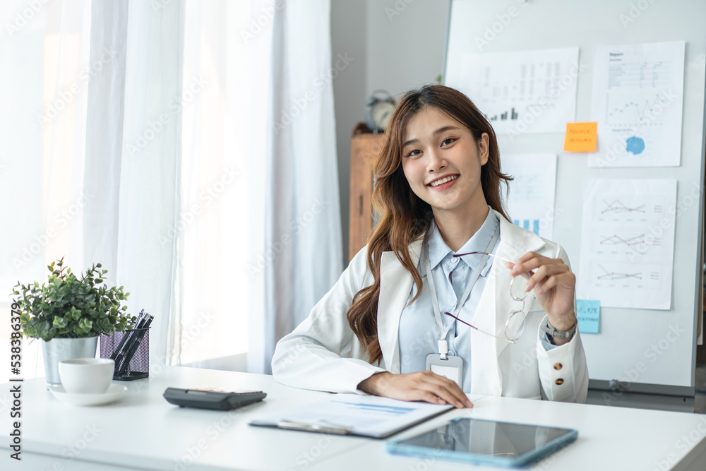 Businesswoman is looking on camera and smiling with confident while sitting to working analysis investment