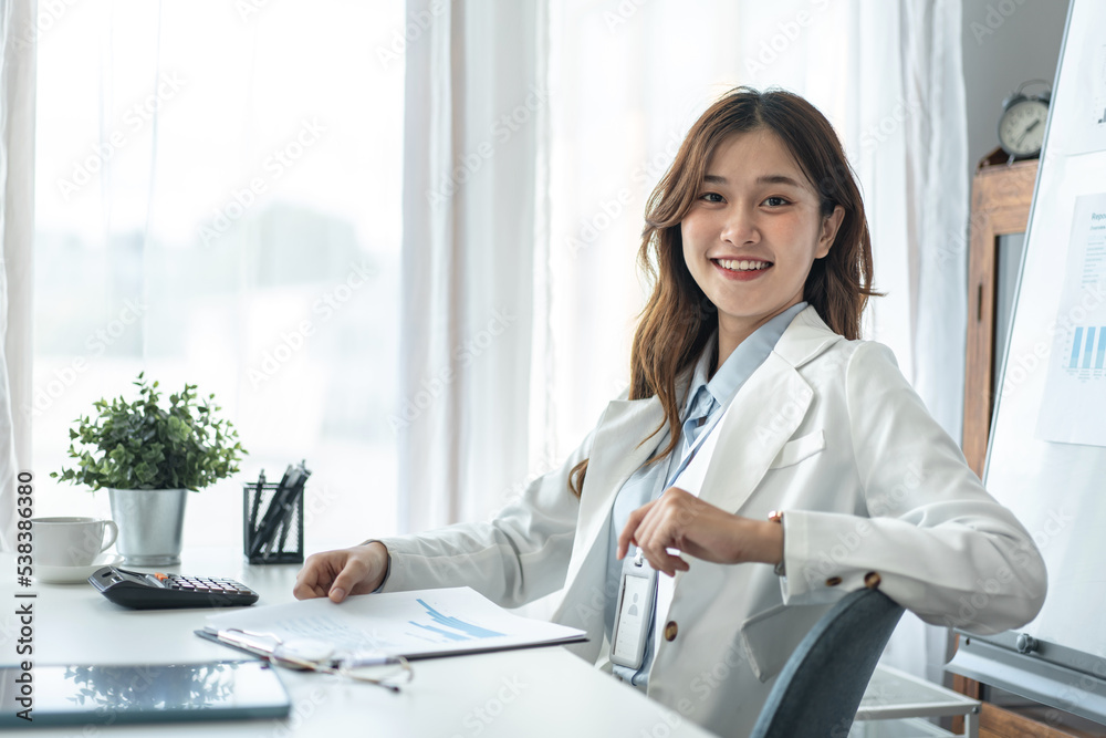 Businesswoman is looking on camera and smiling with confident while sitting to working analysis investment Businesswoman is looking on camera and smiling with confident while sitting to working analysis investment