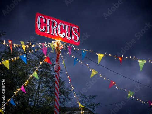 El circo iluminado y decorado con luces de colores y banderillas coloridas al llegar a la ciudad en una noche de tormenta.