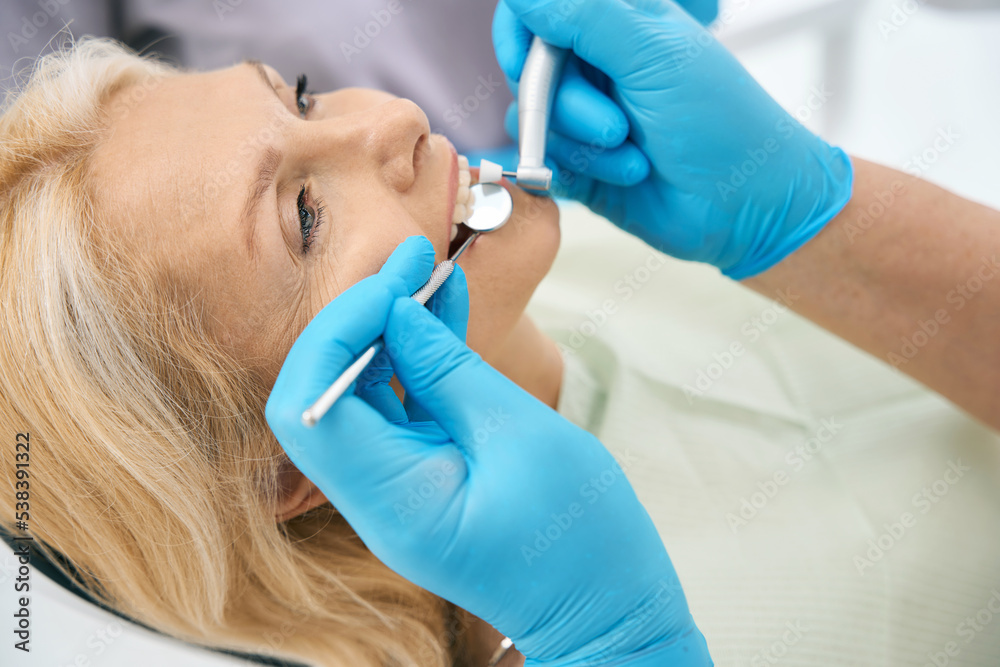Fototapeta premium Beautiful woman patient is receiving dental checkup in medicine center