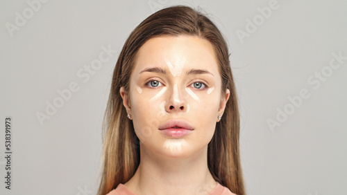 Foundation on the face of a female model. Cosmetic concealer base on a face. Professional makeup. Tutorial makeup master class