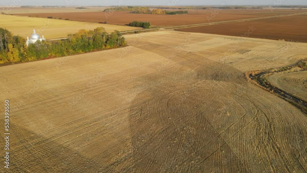 Drone moving forward and turning right over harvested farmland with autumn colors and an old church along one side
Drone moving forward and turning right over harvested farmland with autumn colors and an old church along one side