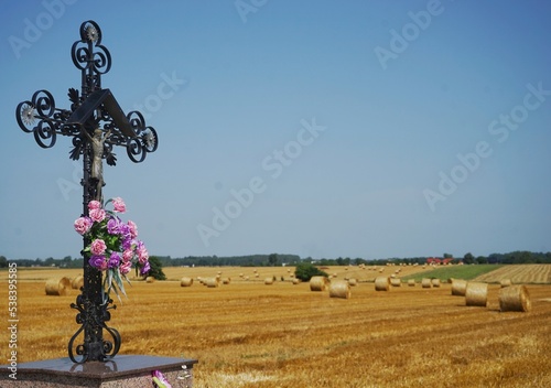 abgemähtes Heufeld in Polen mit christlichem Kreuz im Vordergrund photo