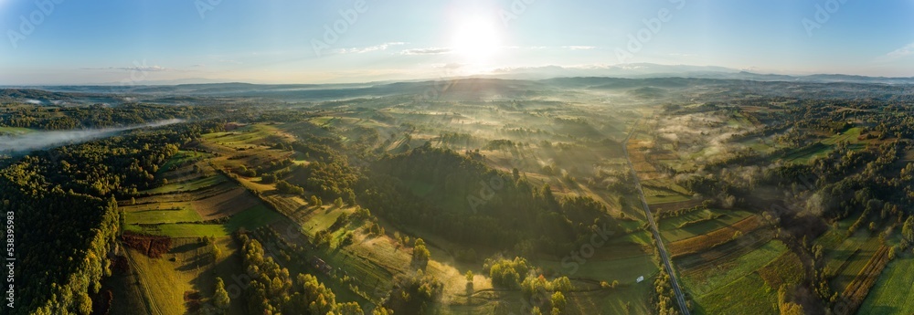 Aerial colorful view of foggy autumn morning over hills and forests, in Soceni village, Romania. Captured from above, with a drone.