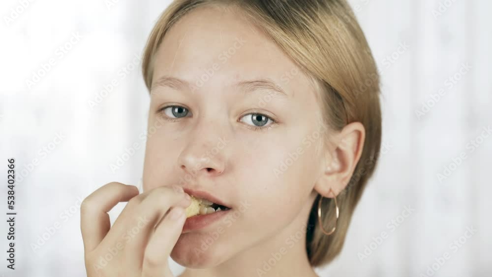 Portrait of a teenager girl eating corn sticks and looking at the camera. Close-up. Snacks. Portrait of a teenager girl eating corn sticks and looking at the camera. Close-up. Snacks.
