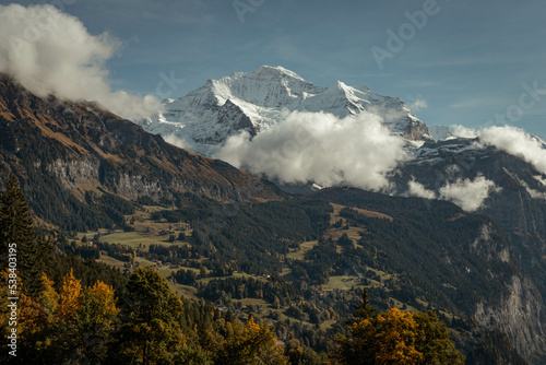 Impressive views over Wengen Switzerland during fall season, trees changing color and new layer of snow on Jungfrau mountain