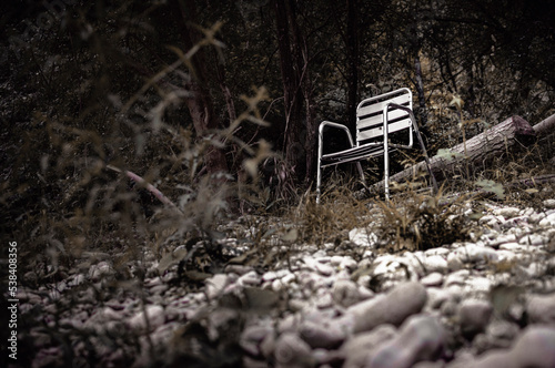 An abandoned chair on the bank of a river.
 photo