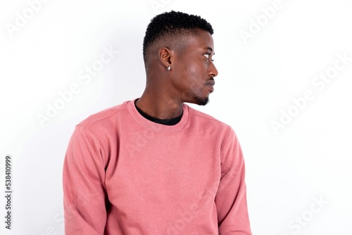 Side view of young happy smiling young handsome man wearing pink sweater over white background © Jihan