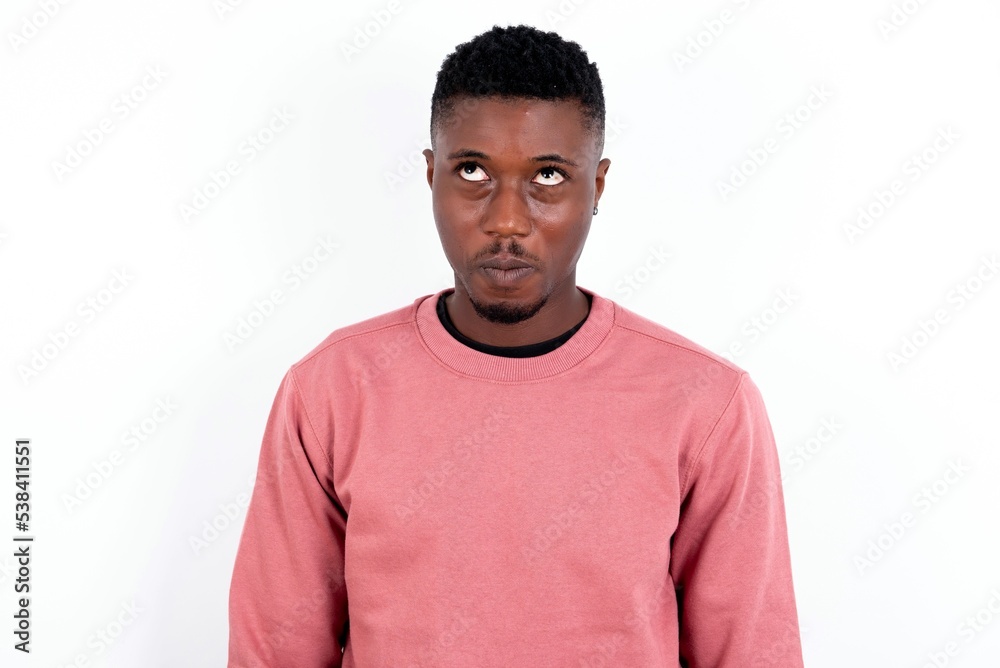 young handsome man wearing pink sweater over white background crosses eyes, puts lips, makes grimace with awkward expression has fun alone, plays fool. young handsome man wearing pink sweater over white background crosses eyes, puts lips, makes grimace with awkward expression has fun alone, plays fool.