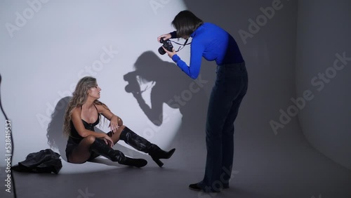 photographing a portrait of a beautiful sexy woman in the studio using a gabo mask and a white cyclorama. woman photographer on the silhouette takes pictures with a digital camera photo