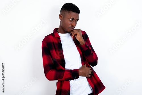 Astonished young handsome man wearing plaid red overshirt over white background looks aside surprisingly with opened mouth. photo