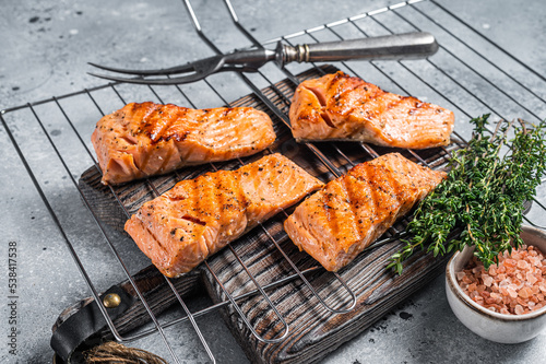 Grilled salmon fillets steaks with salt pepper and herb on grill. Gray background. Top view