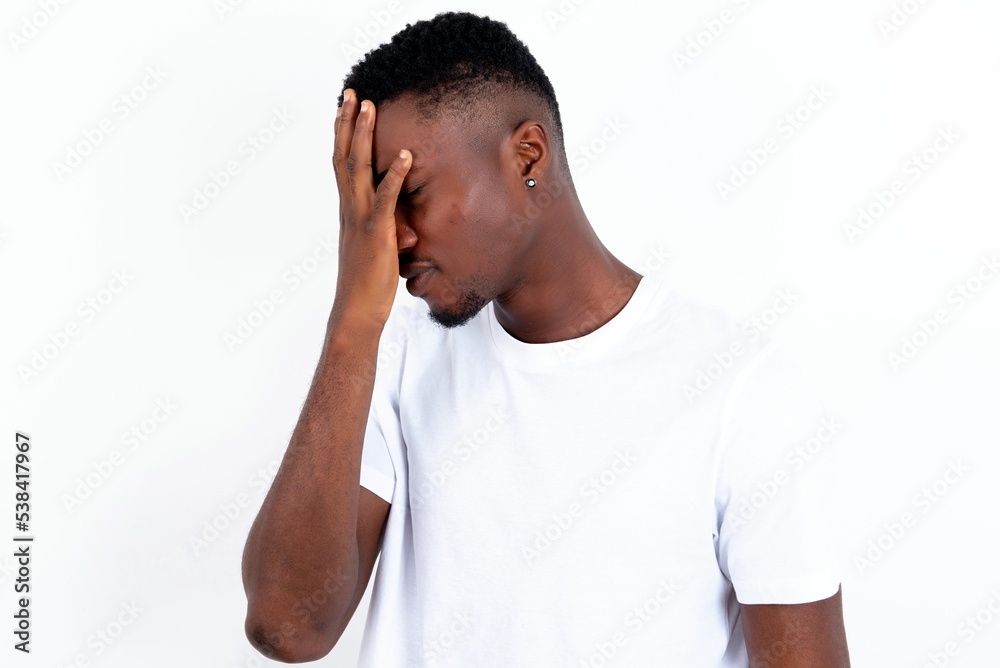 Fototapeta premium young handsome man wearing white T-shirt over white background with sad expression covering face with hands while crying. Depression concept.
