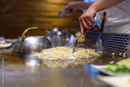 Teppanyaki chef preparing food on hot metal plate