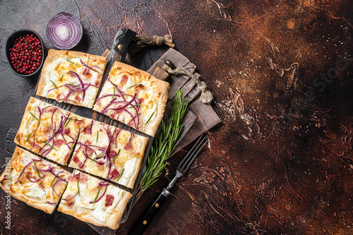 French tarte flambee with cream cheese, bacon and onions. Flammkuchen from Alsace region. Dark background. Top view. Copy space