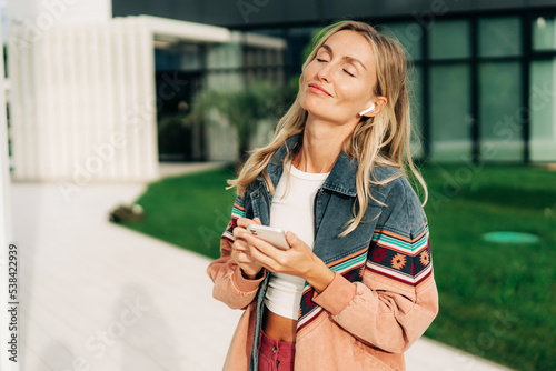 Young stylish blonde woman listens to music in headphones from the phone. photo