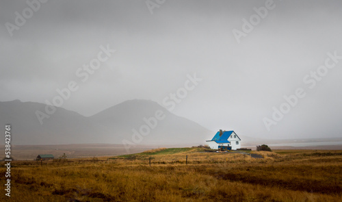 A small colourful blue house in a valley surrounded by mountains in Iceland