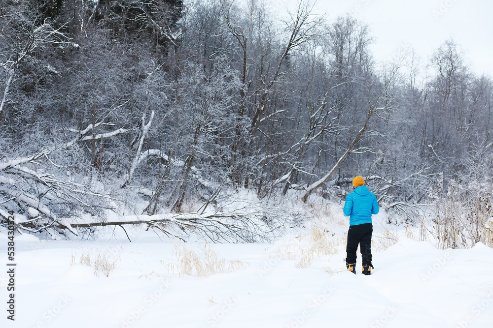 Hiking winter landscape. A man with a backpack travels in winter. A man in a snowy field.