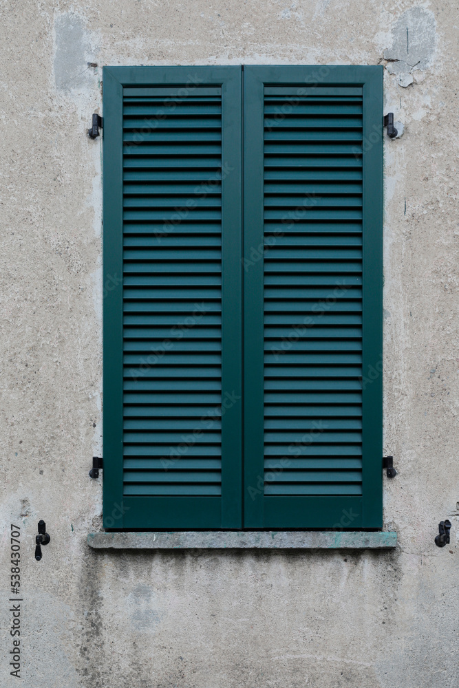 window with shutters, green wooden shutter on a grey housewall as a  background, no person