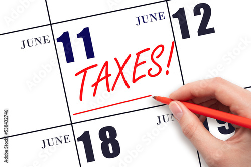Hand drawing red line and writing the text Taxes on calendar date June 11. Remind date of tax payment