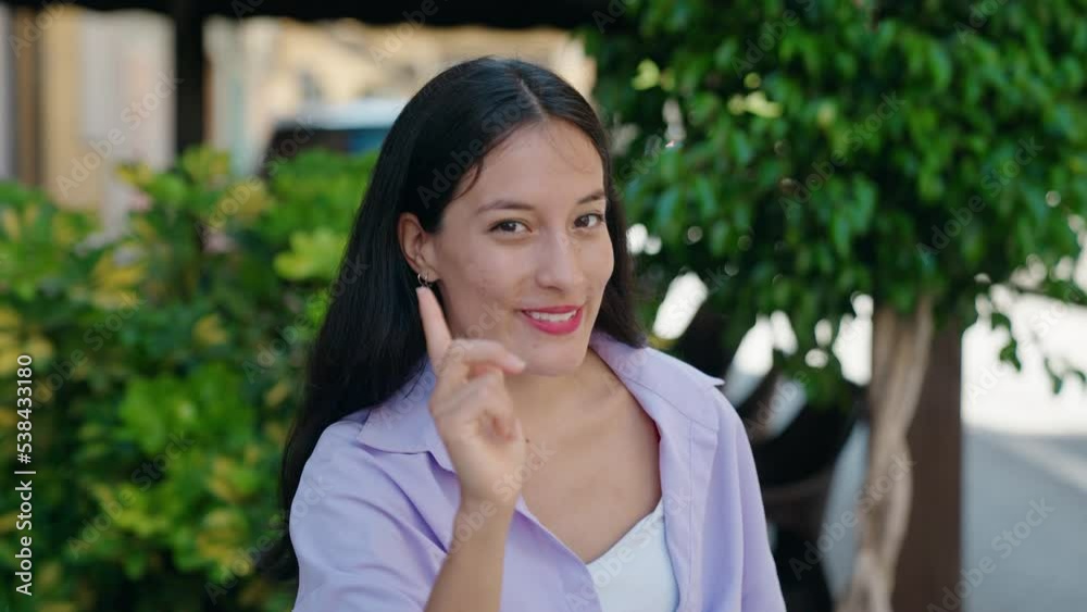 Young beautiful hispanic woman smiling confident doing coming gesture with hand at street Young beautiful hispanic woman smiling confident doing coming gesture with hand at street