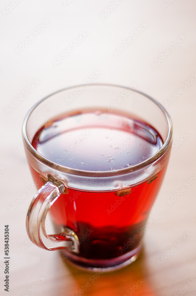 Red berry tea in a transparent cup on the background of a wooden table in a cafe Red berry tea in a transparent cup on the background of a wooden table in a cafe