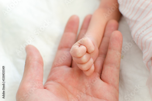 Baby hand on father hand. Tiny Newborn Baby's closed hand on male hand closeup. White background