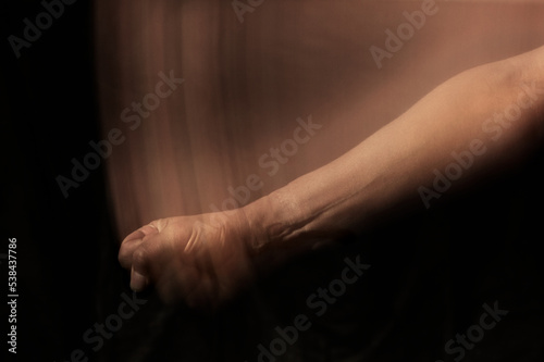 fist hitting the table. hand and forearm with motion trail on black background.