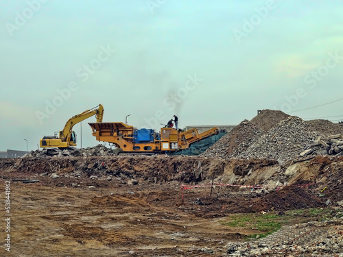 Excavator and portable cone rock crusher in a quarry