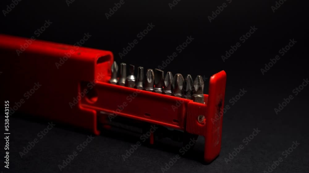 Close up crafts of bolts, screws, nuts, washers, mechanical part, drill bits red package, with blue light background. black background. precision work. Work as a carpenter. Joinery and construction wo Close up crafts of bolts, screws, nuts, washers, mechanical part, drill bits red package, with blue light background. black background. precision work. Work as a carpenter. Joinery and construction wo