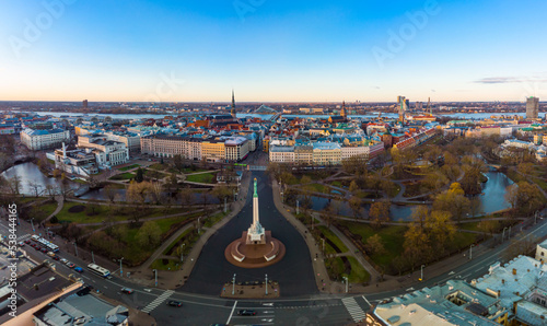 Amazing Aerial panoramic view to Monument of freedom with old town in background, during autumn sunrise. Milda - Statue of liberty holding three Golden stars over the city. Riga, Latvia, Europe.