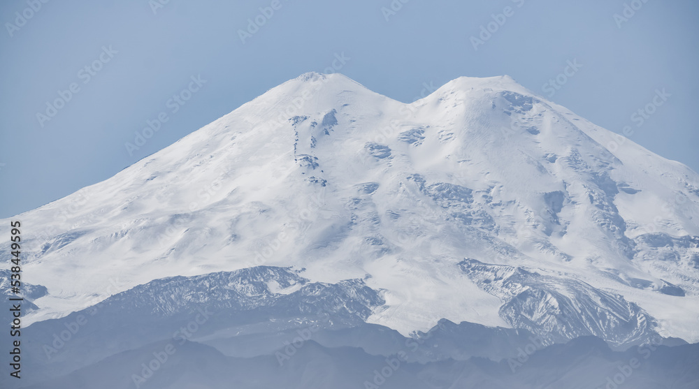 Mount Elbrus in the approximation is distinguished by two peaks with rocks, snow and glaciers panoramic view with a clear sky, a warm autumn day
